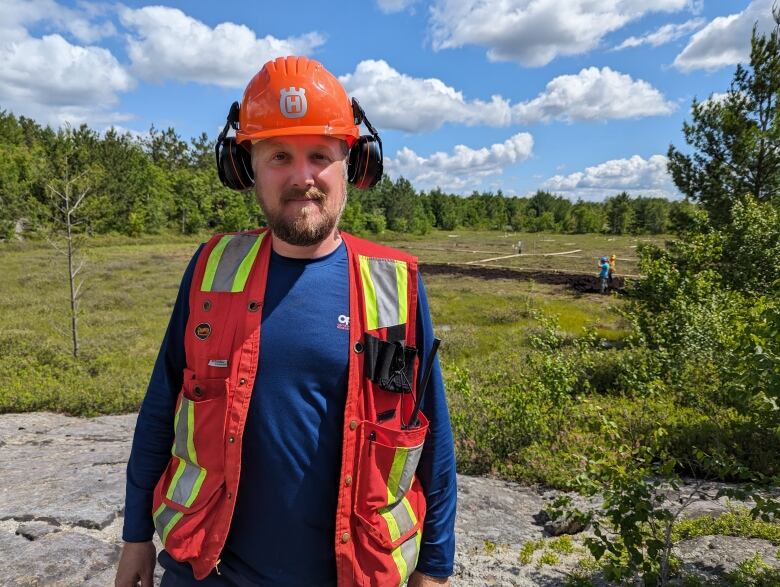 A bearded man wearing a safety vest and orange hard hat.