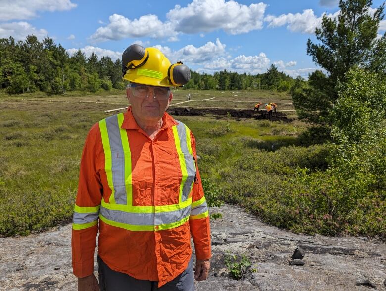 An older man wearing an orange safety vest.