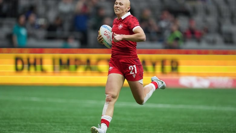 A rugby player in action running in the field with the ball. 