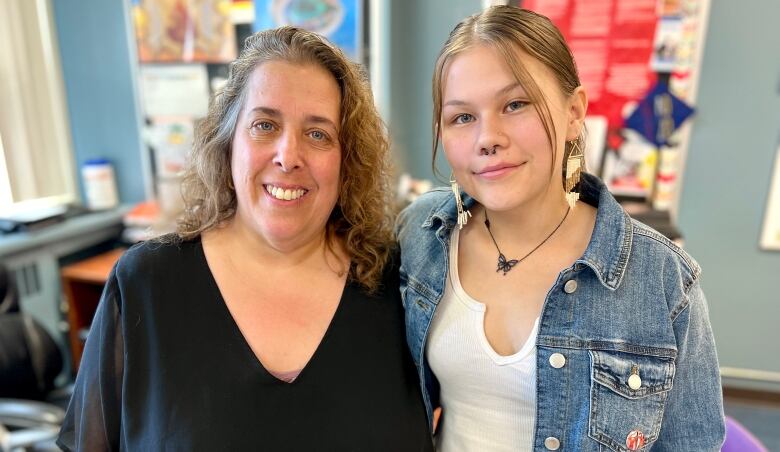 Two women embrace each other and smile to the camera.