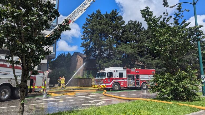 Fire trucks and firefighters spew water at a building.