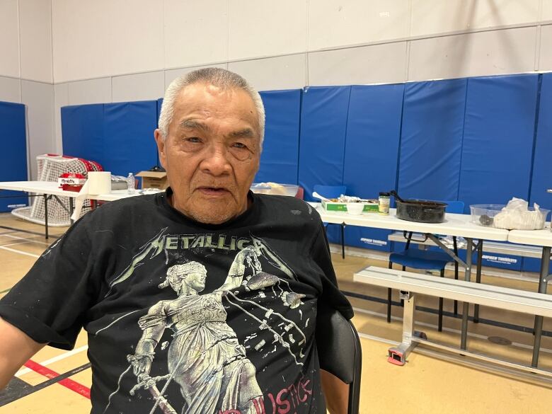 A man sits in a gymnasium.