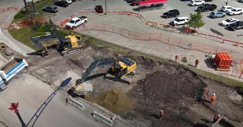 an aerial view of a construction site. heavy machinery is moving dirt over an excavation site.