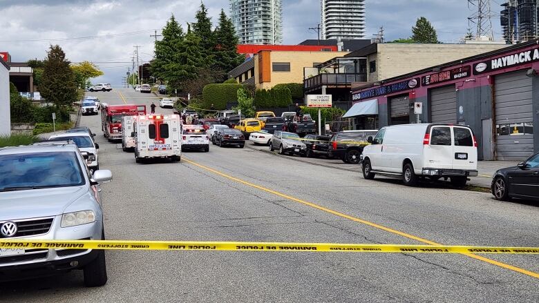 Yellow police tape blocks off road. Two ambulances are in the middle of the road.