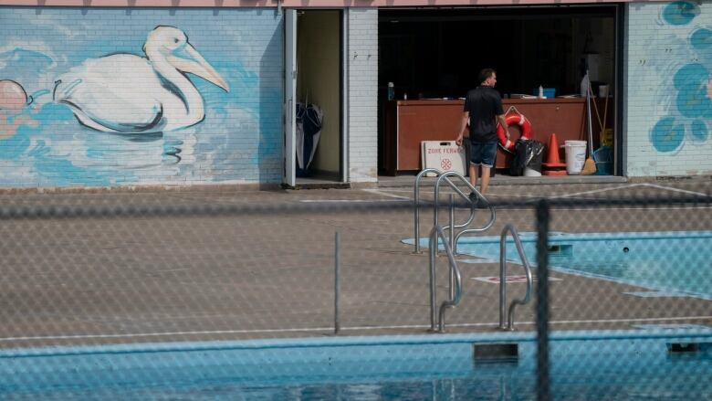 Workers preparing pool with mural of bird on wall. 