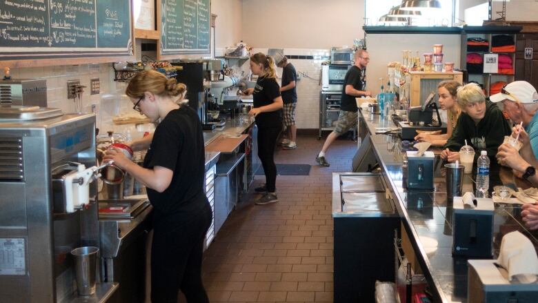 Young people work behind the counter at a busy diner.