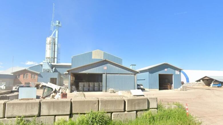 Blue industrial buildings are pictured on a sunny day.