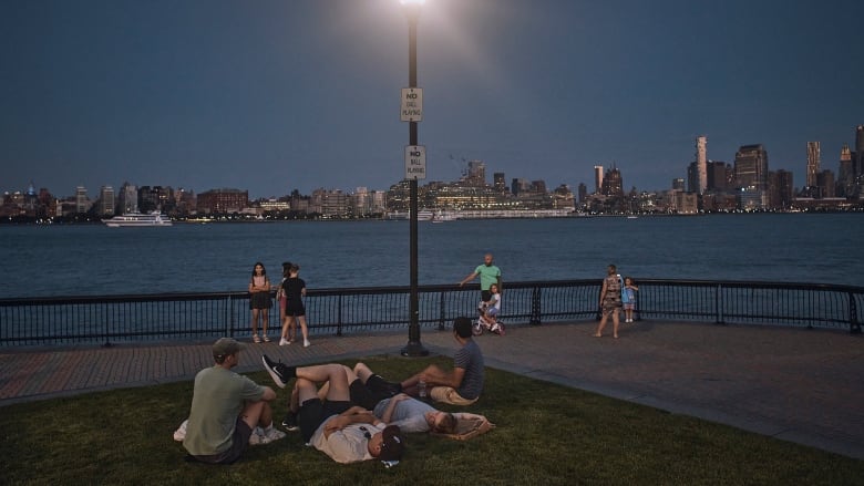 People spend time at the park at dusk during a summer heat wave