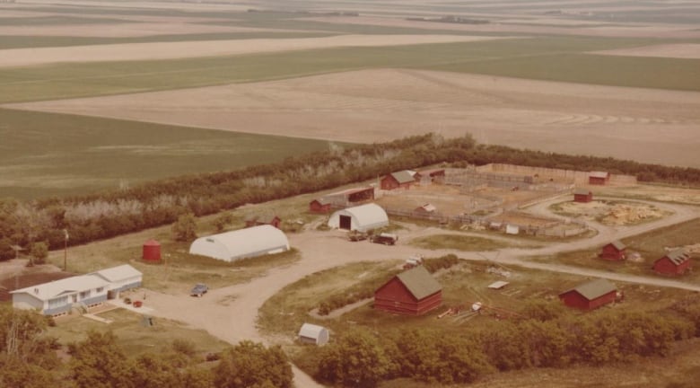 An aged photo of a house and farm buildings.