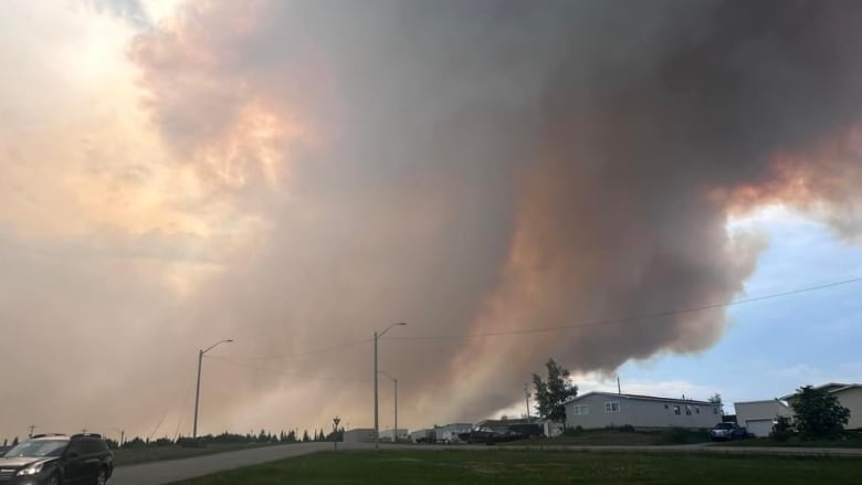 Orange smoke from wildfire takes over community with blue skies.