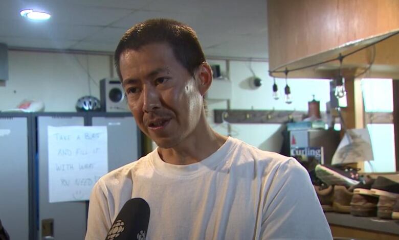 A man wearing a white shirt talks into a CBC microphone 