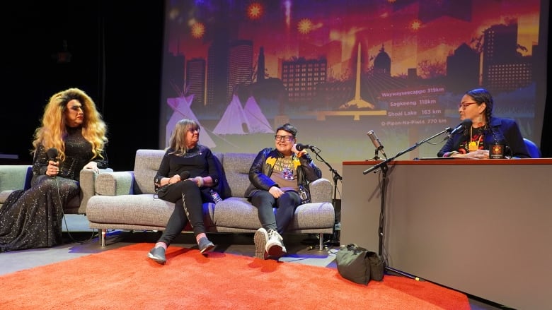 Four people sit on a stage with a colourful backdrop.