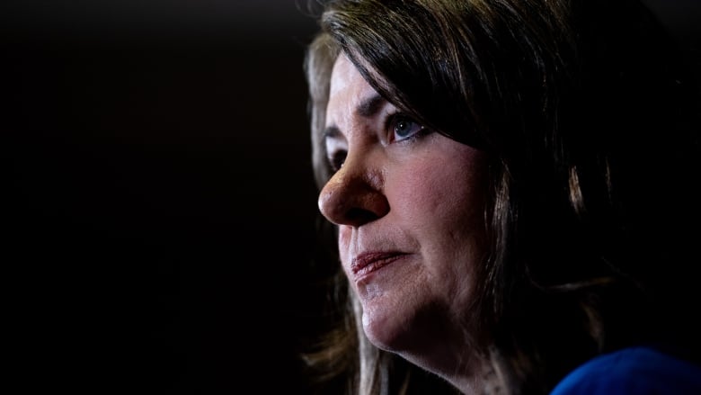 A woman is pictured in front of a black backdrop.