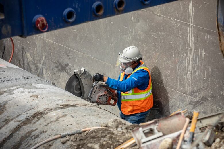 a construction worker saws a giant pipe.