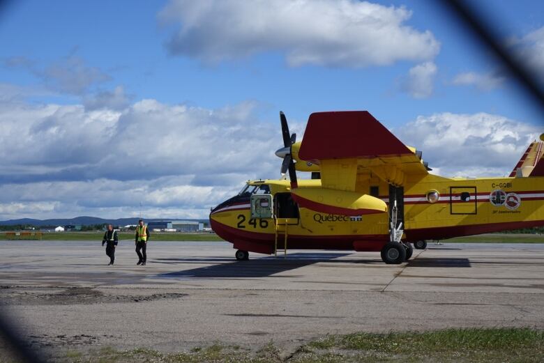 A large yellow water bomber sitting on a runway.