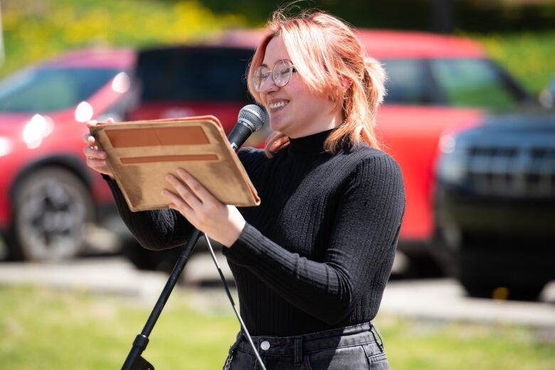 A person with pink hair standing at a microphone