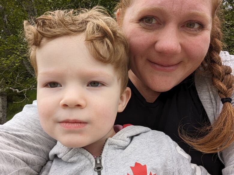 A woman with long red hair holds her young son. 