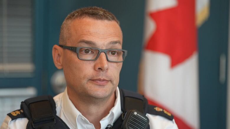 A man with glasses and an RCMP uniform speaks in an office.