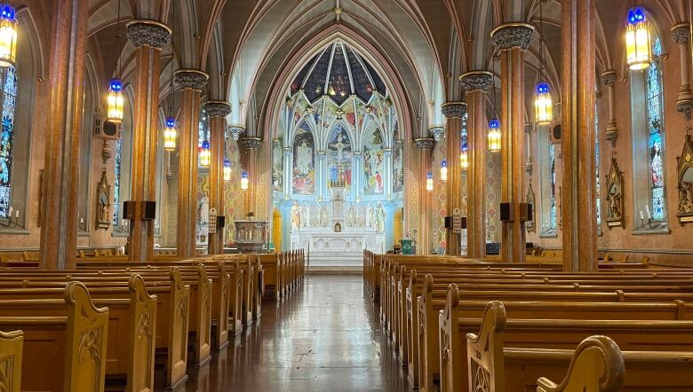 The interior of an ornate gothic church with rows of pews and a large pipe organ at the rear.