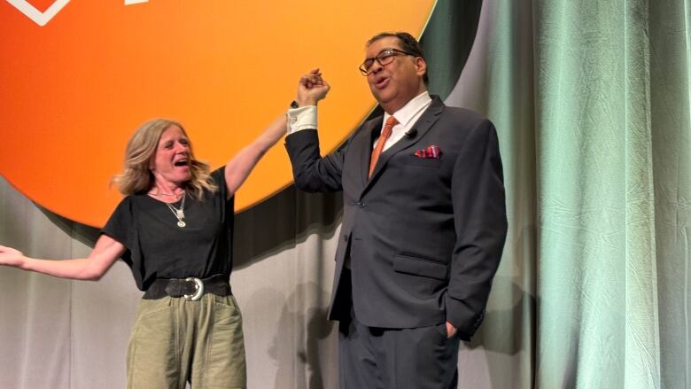 Rachel Notley holds Nenshi's hand and cheers.