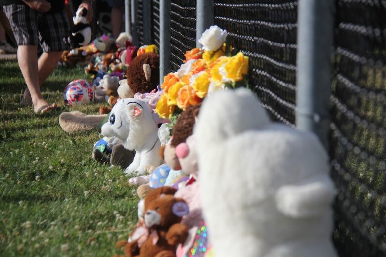 Stuffed animals along a chain link fence