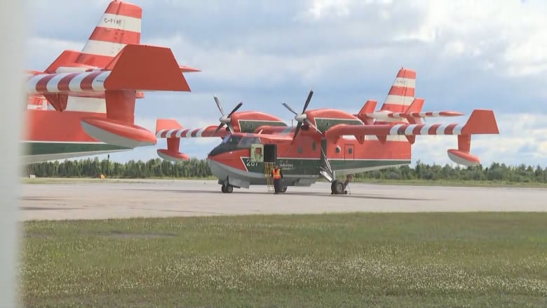 Two water bomber aircraft sit on a runway.