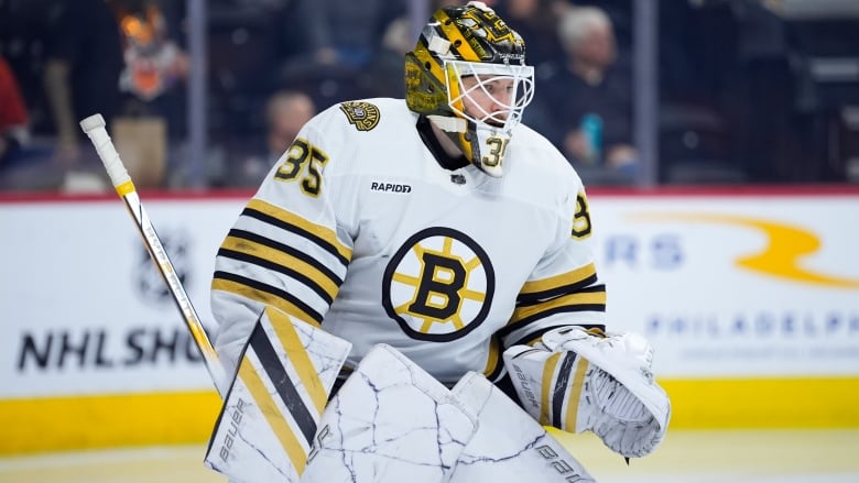 A male ice hockey goaltender looks off into the distance on the ice during a game.