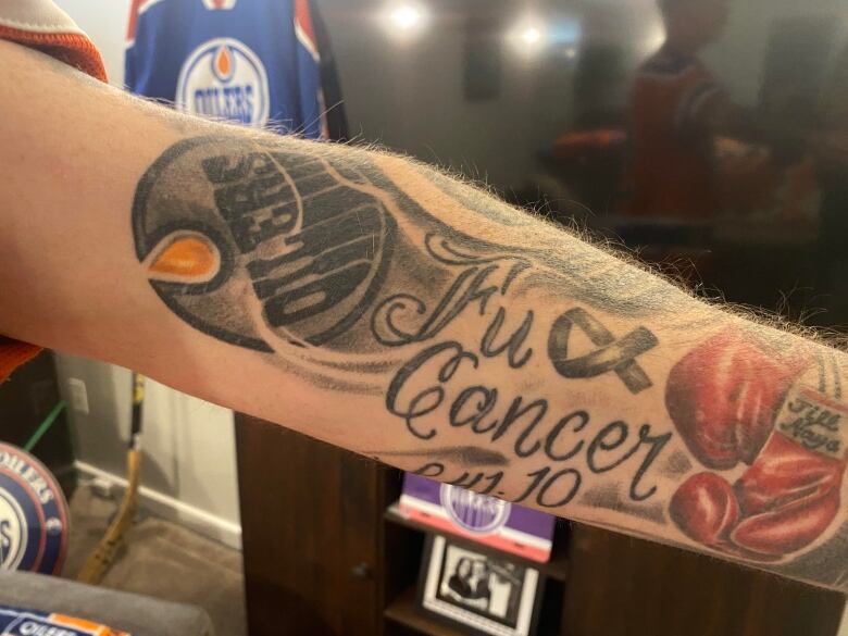 A man's arm can be seen with tattoos of the Oilers logo and 'FU cancer' written on it.