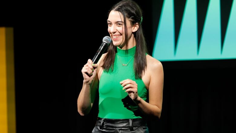 A woman in a green tank top with a microphone.