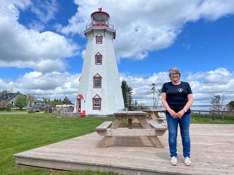 A woman stands with a lighthouse in the background 