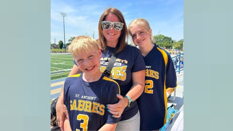 A mother and her two children at a school running track.