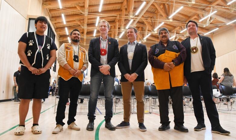 Six men standing in a wooden gymnasium.