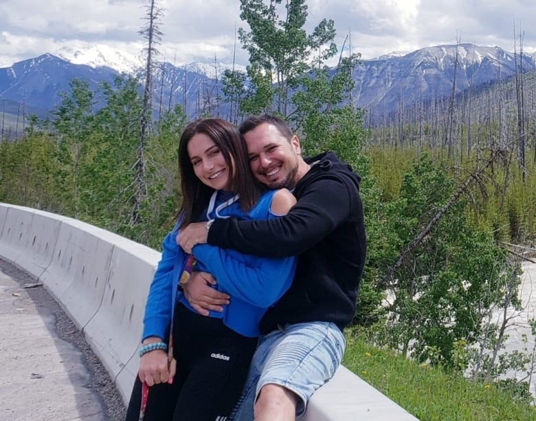 A couple smiling infront of a mountain range.