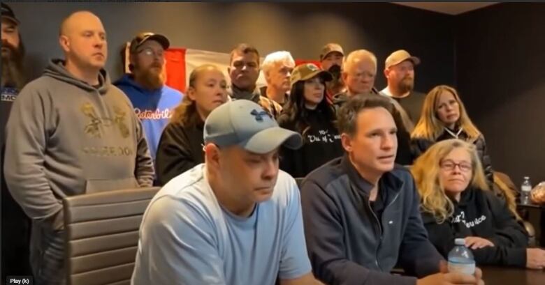 A group of people crowded around a table at a press conference. 