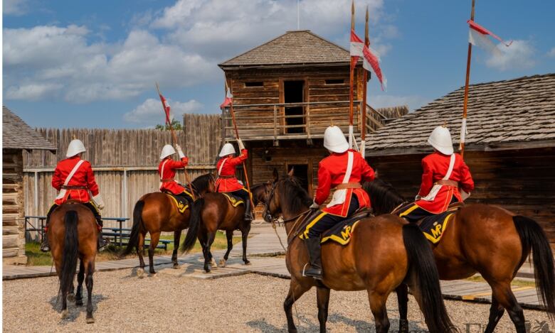 People on horseback and wearing red surge uniforms file out of a wooden fort.