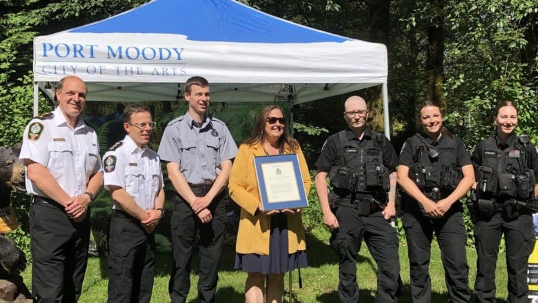 A woman holds a plaque at the centre of a line of uniformed conservation officers.