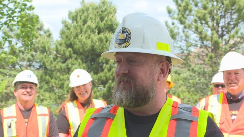 A man in a yellow vest and white construction helmet.