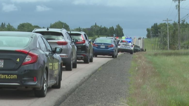 A long row of traffic with debris from an accident visible in the distance. 