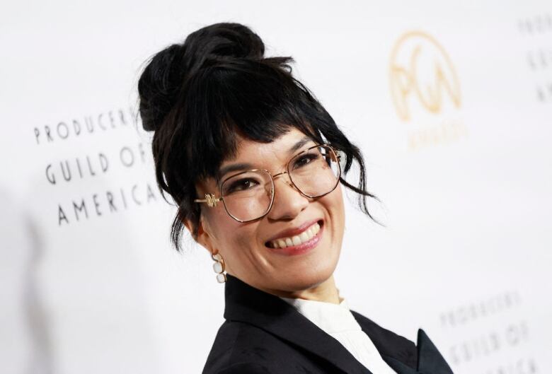 A woman in glasses smiles at the camera