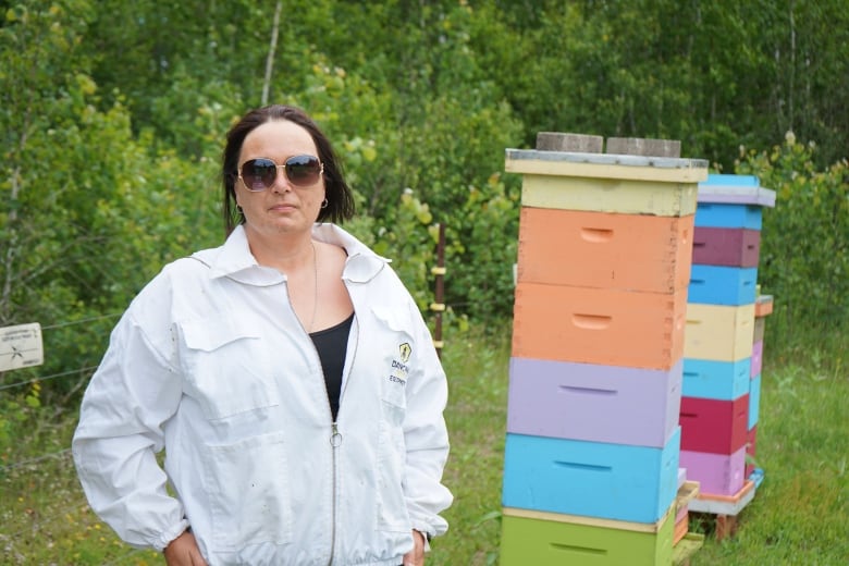 A woman posing in front of her hives.