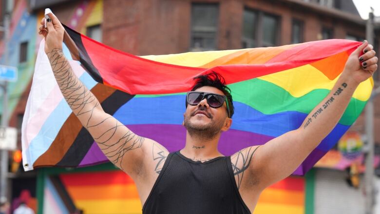 A man holds up a rainbow flag.