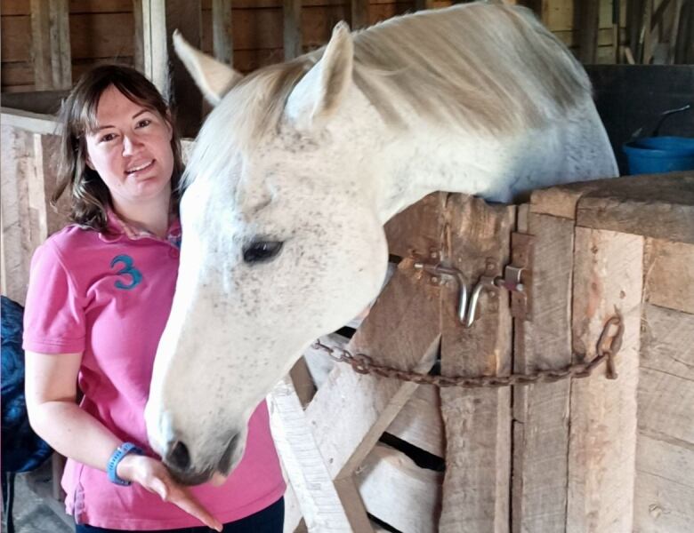 a woman holds her hand by a horses mouth