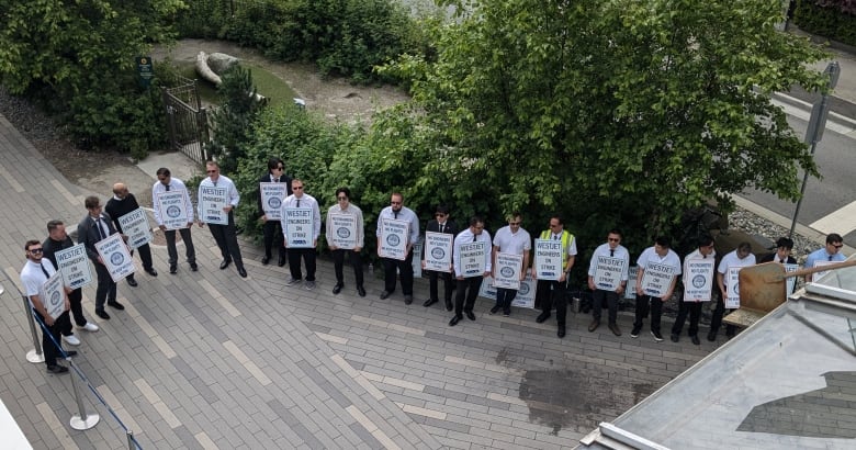 Union members holding signs stand together in a picket line.