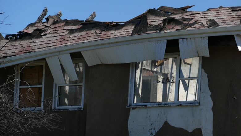 A house shows burned shingles on a roof. 