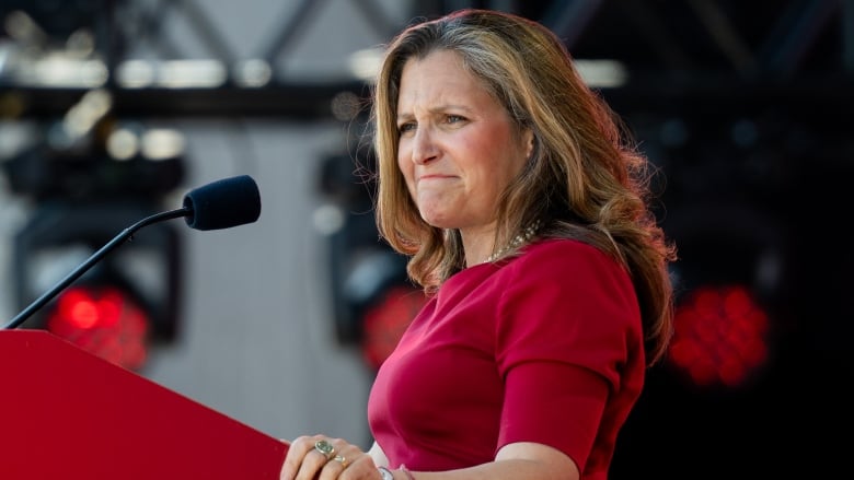 Minister of Finance and Deputy Prime Minister Chrystia Freeland wearing a red dress, standing at a red podium.