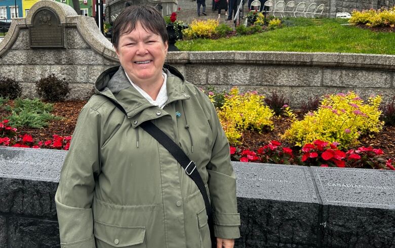 Woman with short brown hair and green jacket smiles