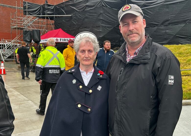 Woman with white hair and nurses cap, and man in grey cap. 