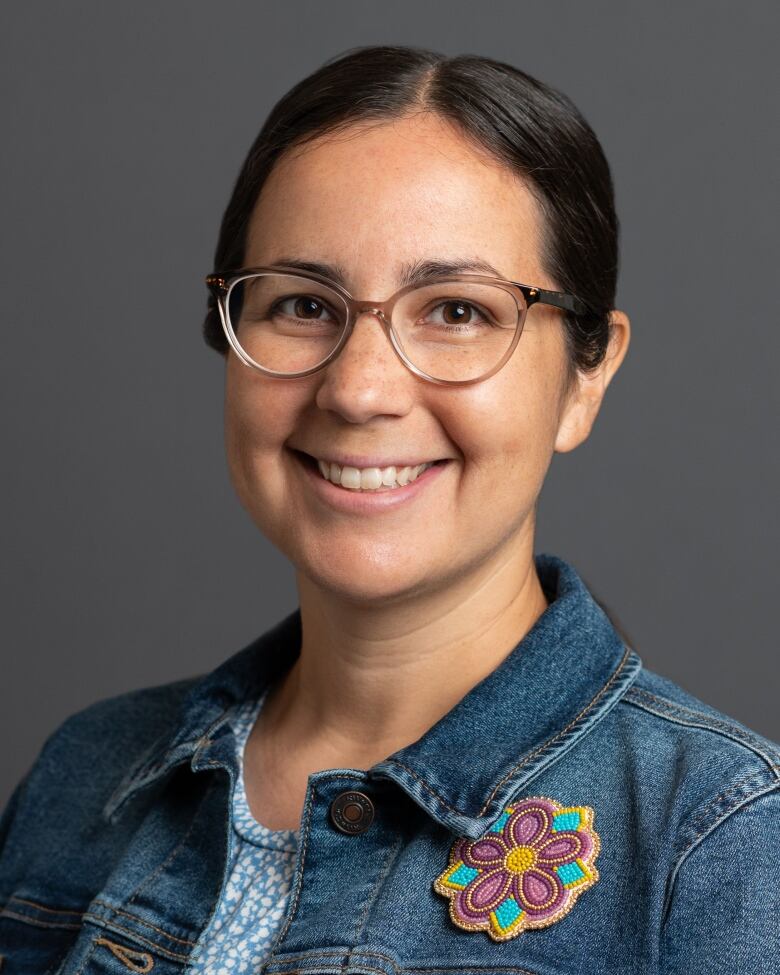 Melody smiles in a headshot wearing a denim jacket with her hair pulled back.