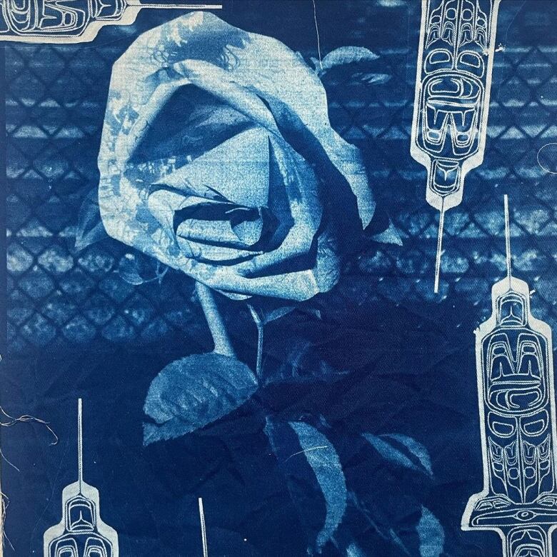 A piece of artwork, primarily dyed blue, shows a rose flower with a chain-link fence in the background. It is surrounded by syringes that are embossed with intricate designs.