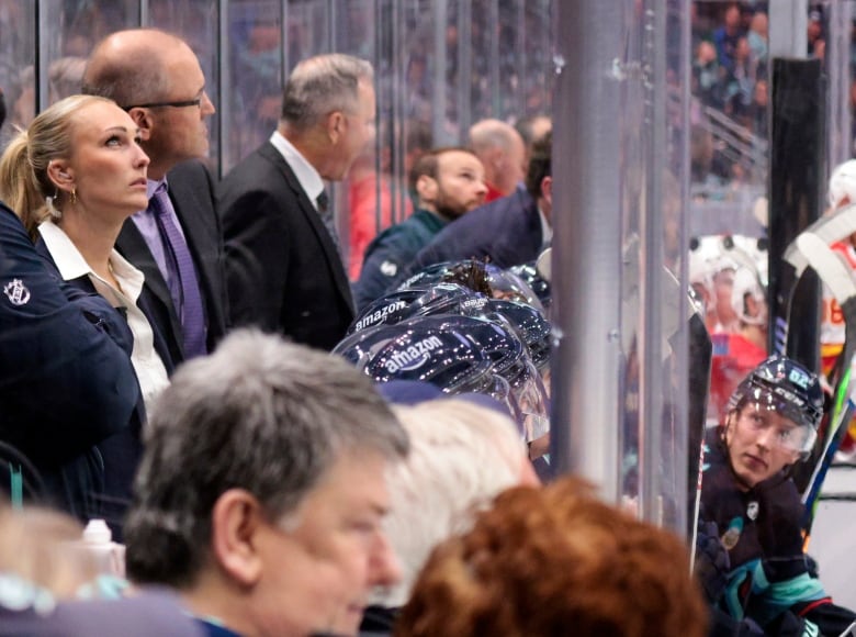 Female coach, assistant coach for the Coachella Valley Firebirds, works alongside Seattle Kraken coaches behind the bench during the second period of an NHL preseason hockey game against the Calgary Flames, Monday, Sept. 25, 2023, in Seattle.